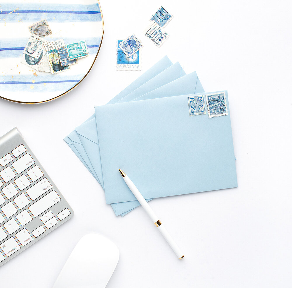 stationery, envelopes and a pen sitting on a desk with a keyboard