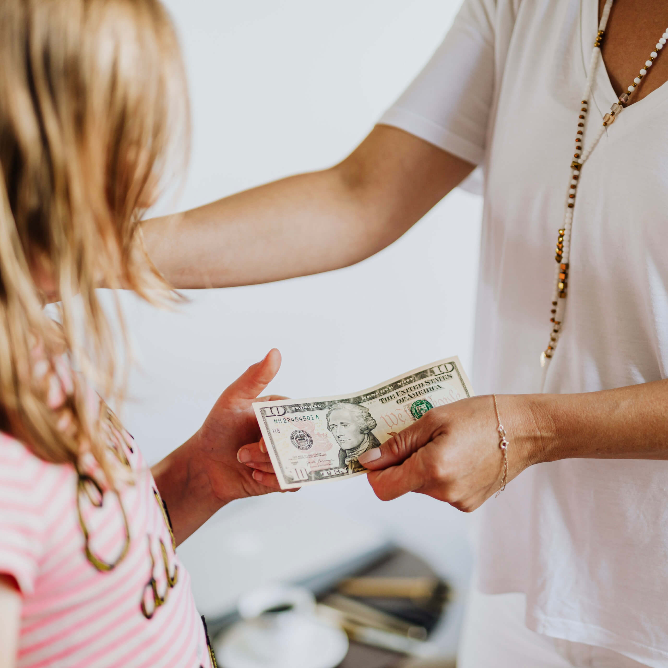 woman handing $10 to a little girl