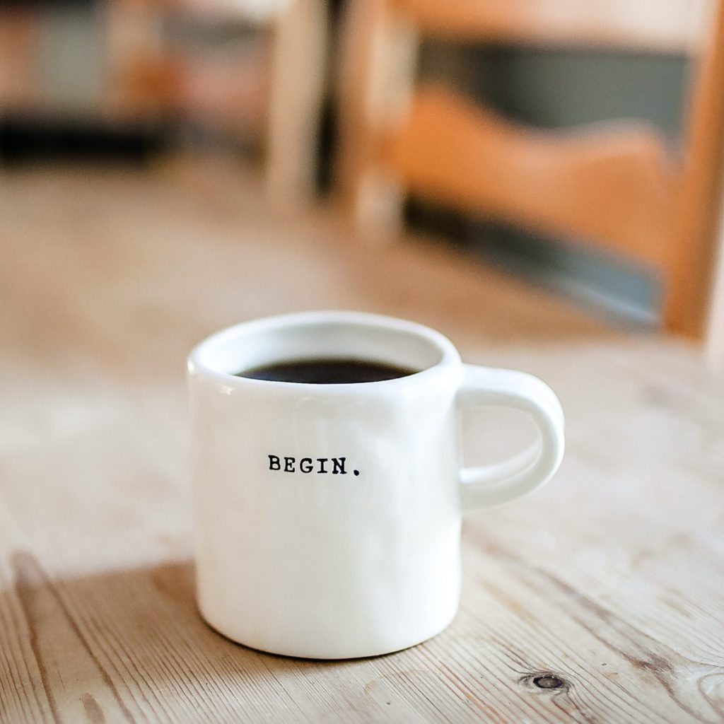 white coffee mug, with coffee in it. The word begin on the front | where does organization begin | Positively Jane