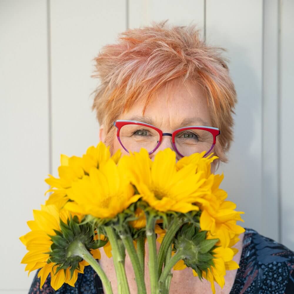girl holding yellow flowers in front of her face so only her eyes show