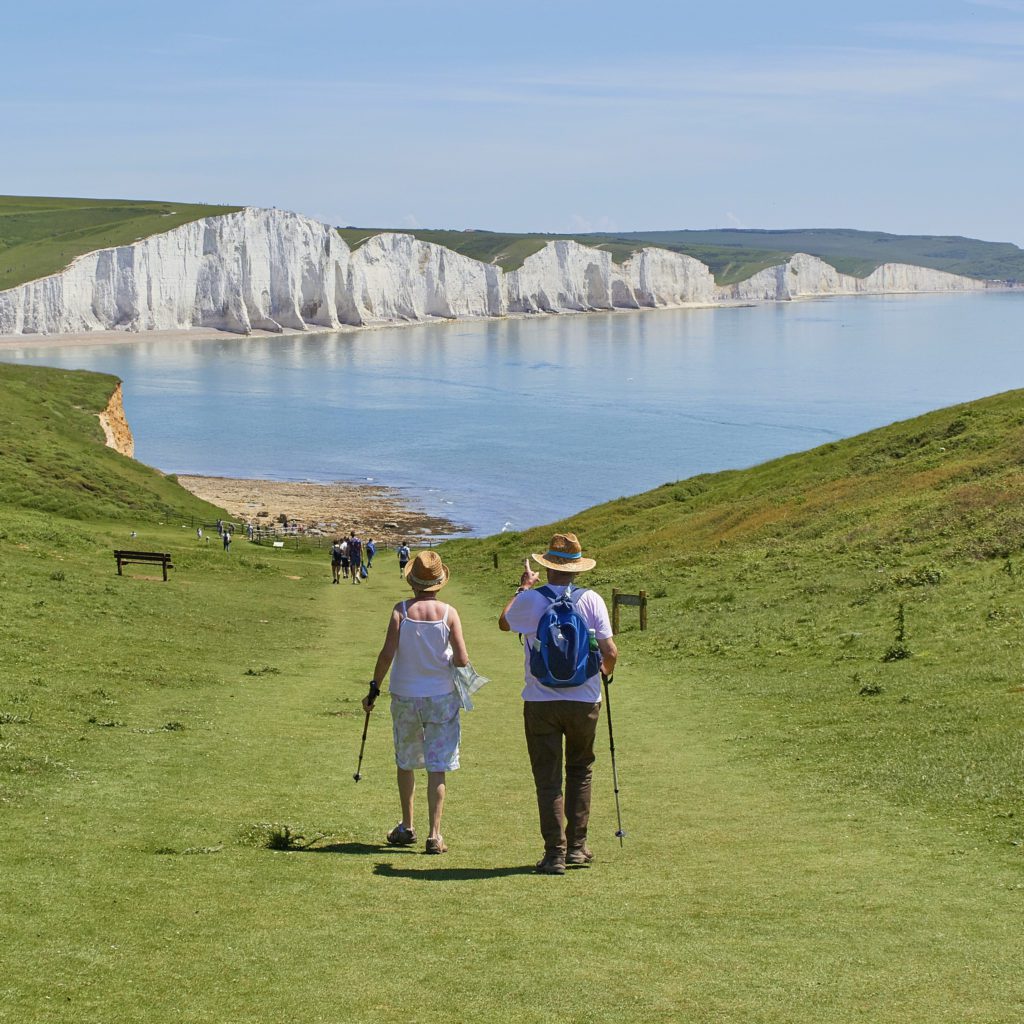 man and woman walking on a green path towards a lake  | are you ready for retirement  | Positively Jane