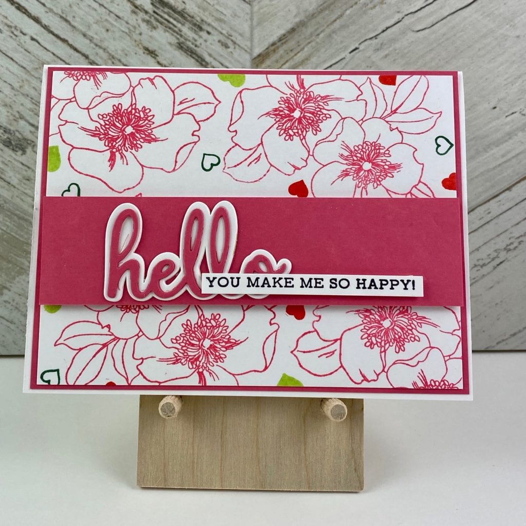 hand stamped card with pink flowers on the background and a pink strip across with a large hello and a you make me so happy sentiment