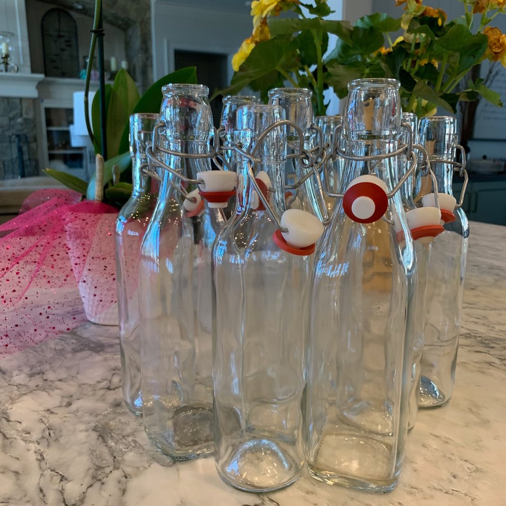 empty Kombucha bottles sitting on a counter waiting to be filled