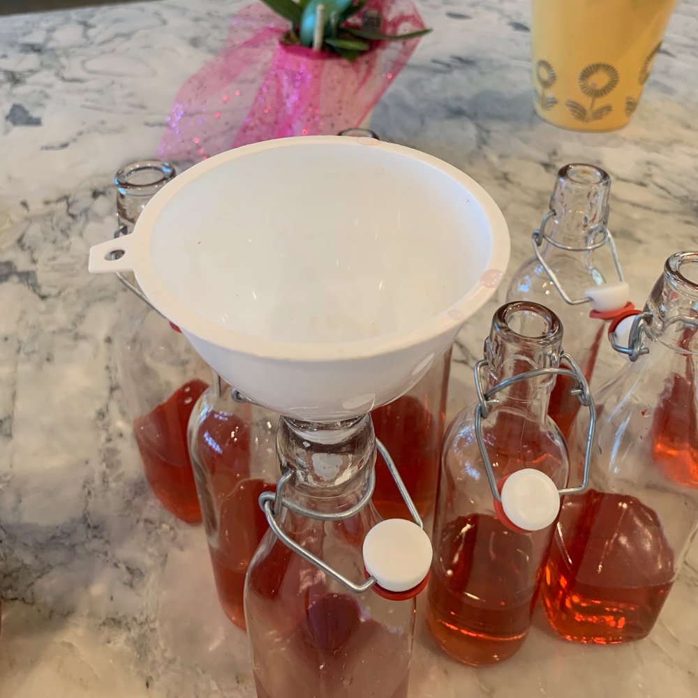 kombucha bottles filled with 1/3 juice using a funnel