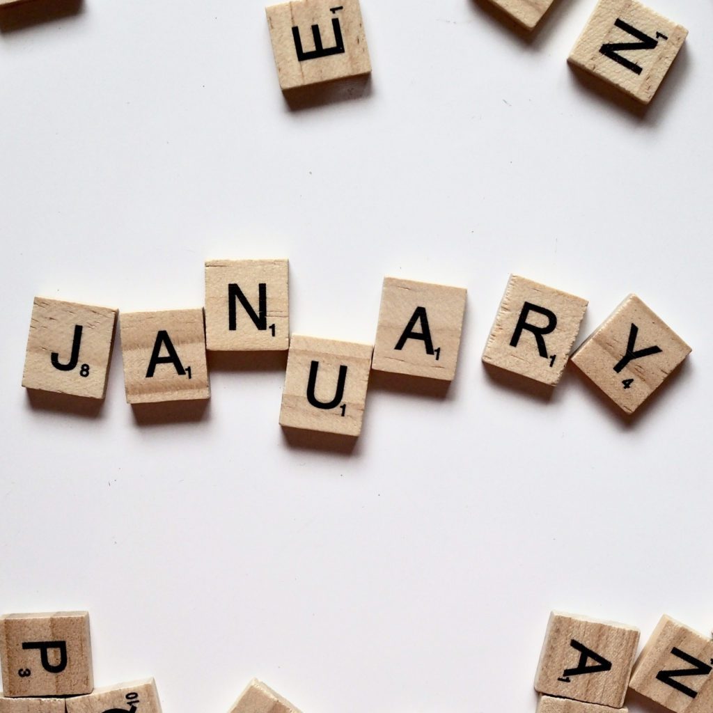 the word january spelled out with scrabble tiles | how to have a debt free january | Positively Jane