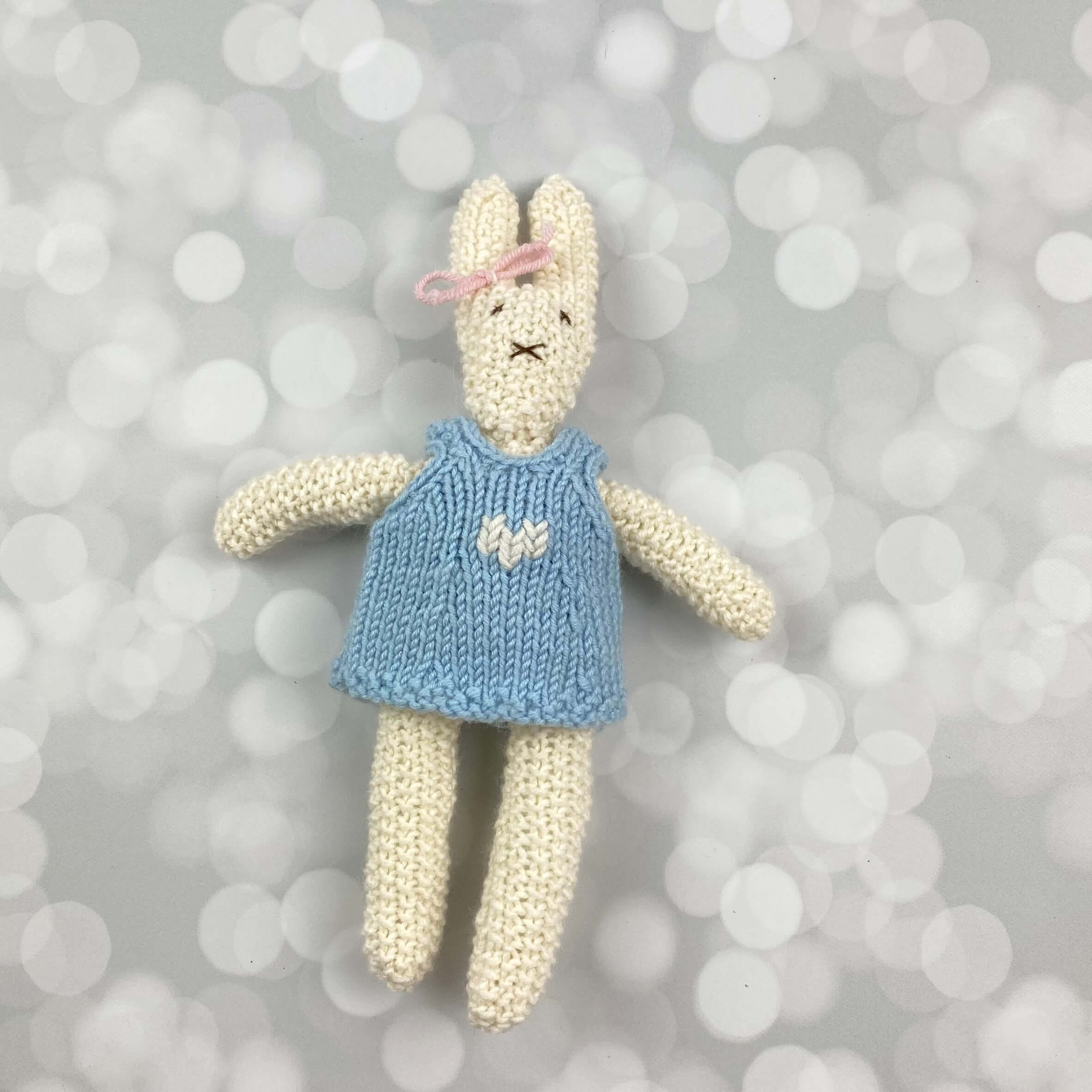 hand knitted rabbit with a blue dress. About 8" tall
