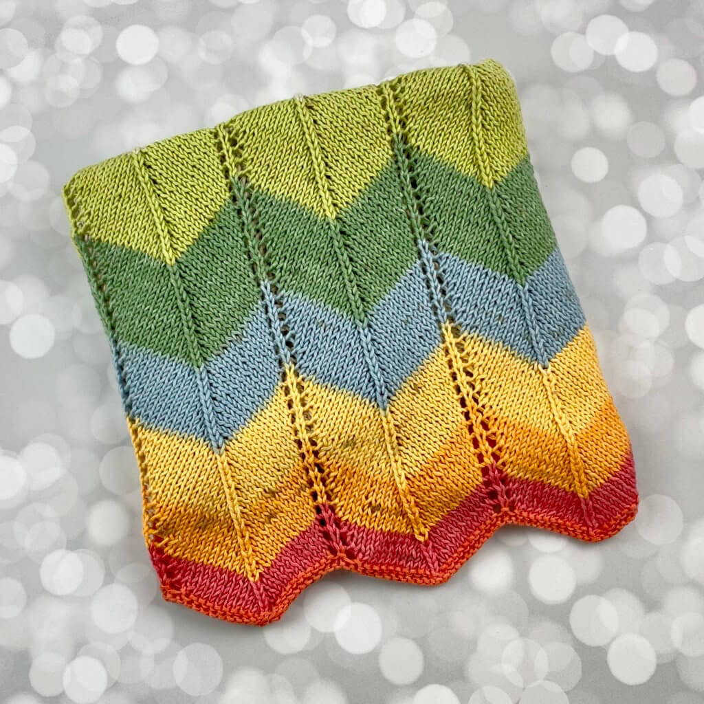 handmade knitted baby blanket with a colorful chevron pattern on the end - folded nicely