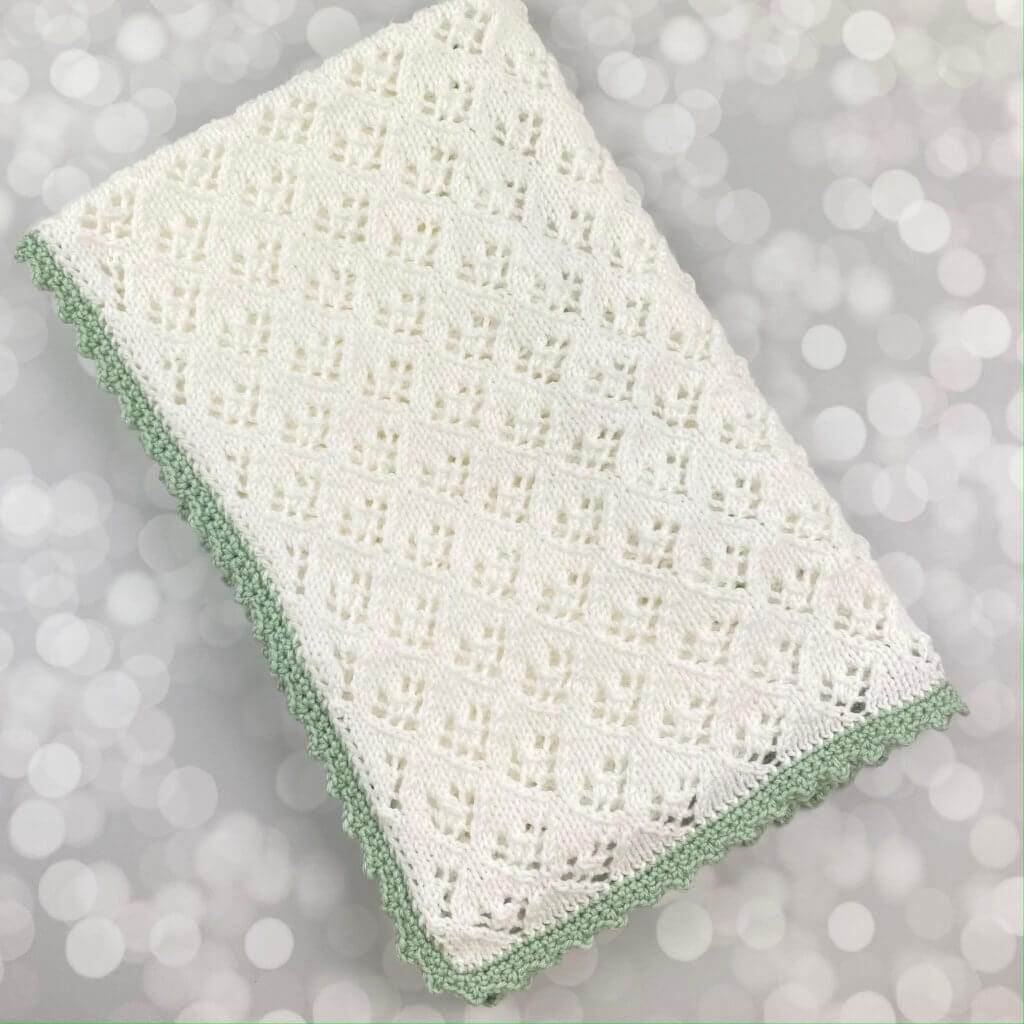 handmade white baby blanket with lite green edging - folded flat