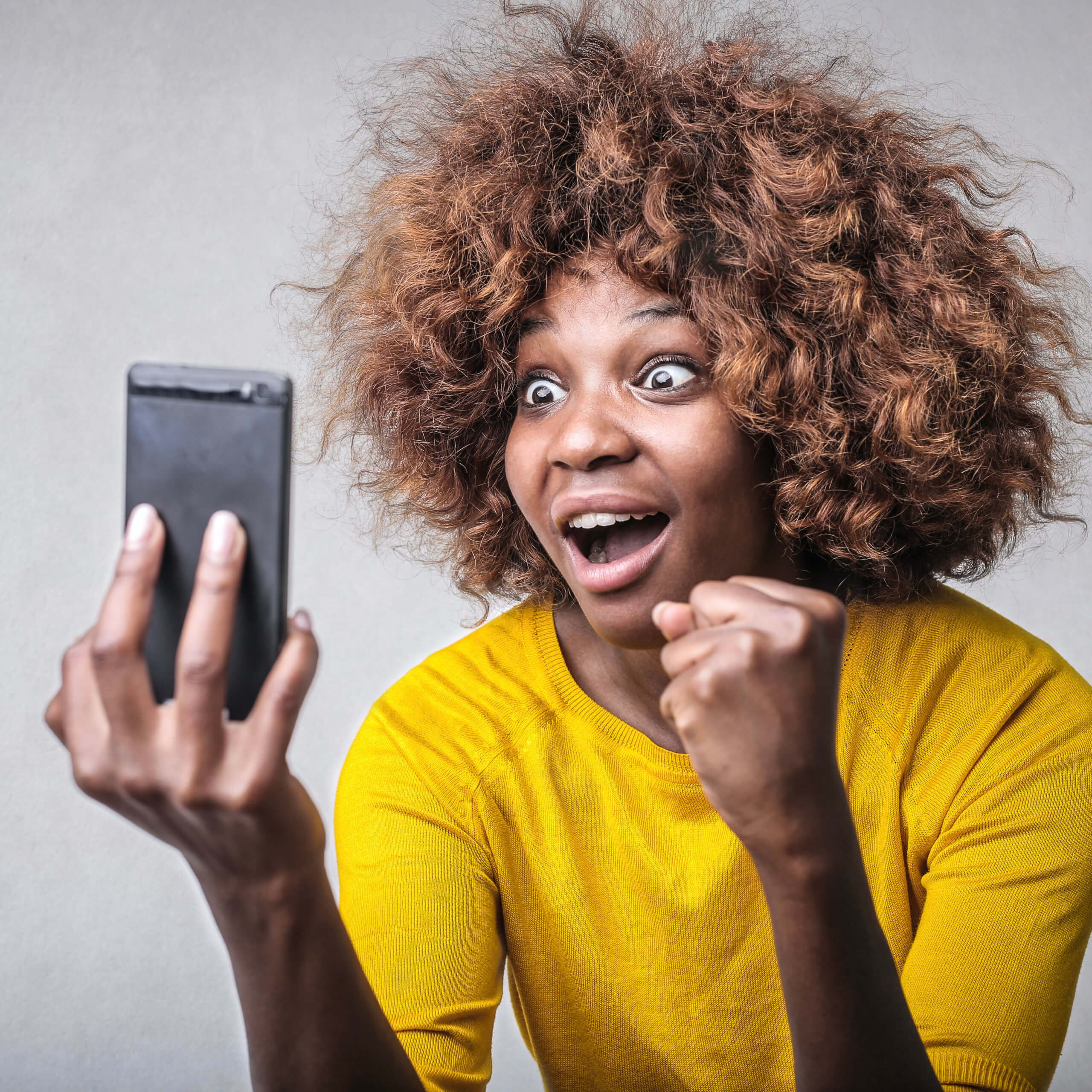 woman looking at her phone with a very surprised and excited look on her face