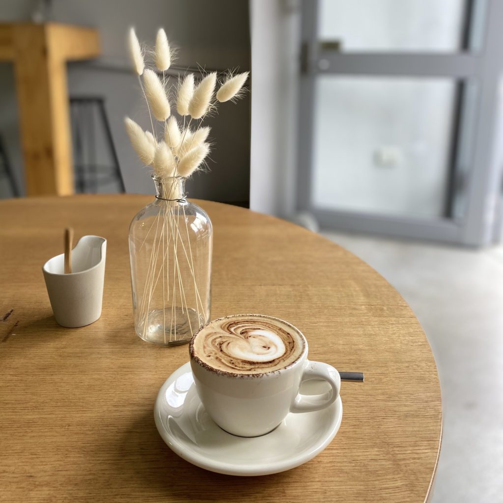 round table with a cup of coffee and a vase with grasses in it. the coffee has a heart made with milk on top | starting your day | Positively Jane