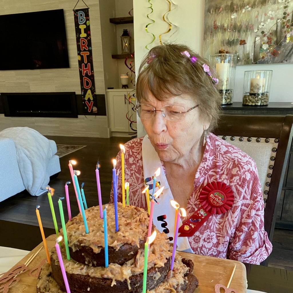 older woman blowing out her birthday cake candles