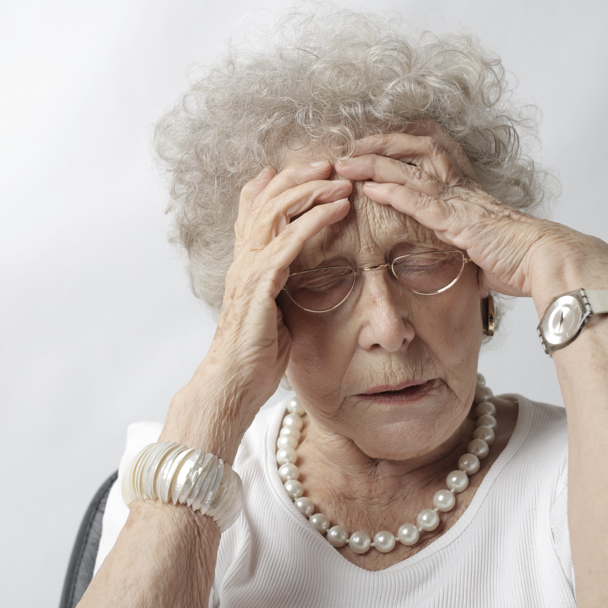 old woman with her head in her hands looking worried
