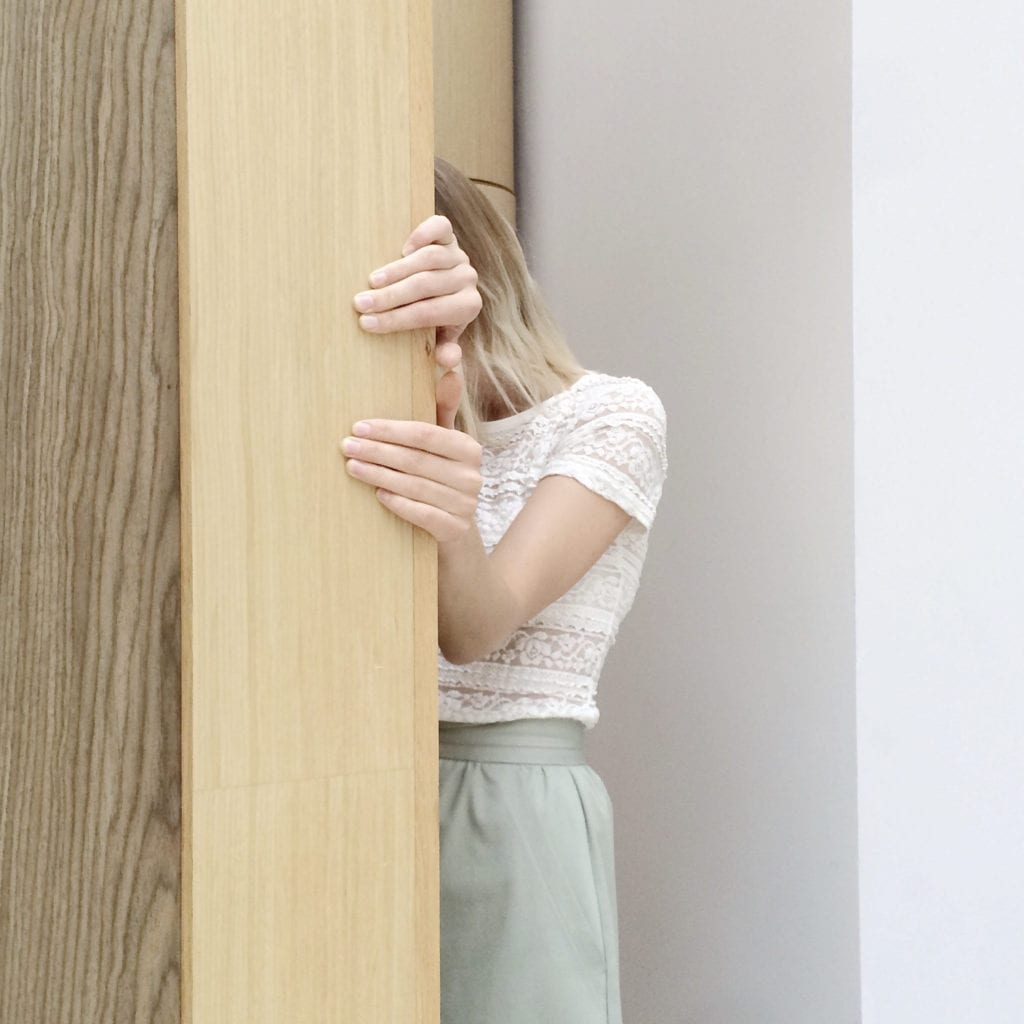 girl hiding behind a wall because she is fearful