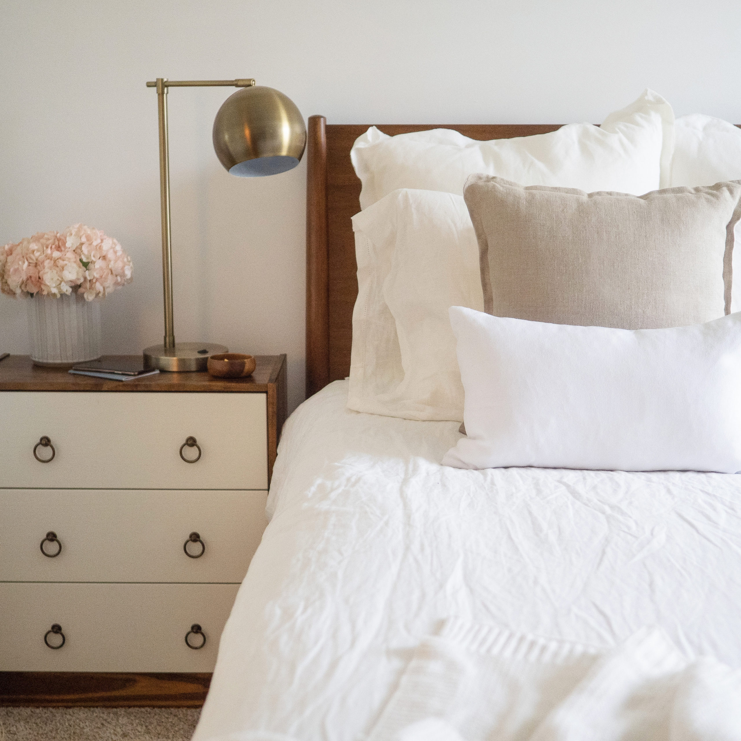 a bed made with white sheets and comforter
