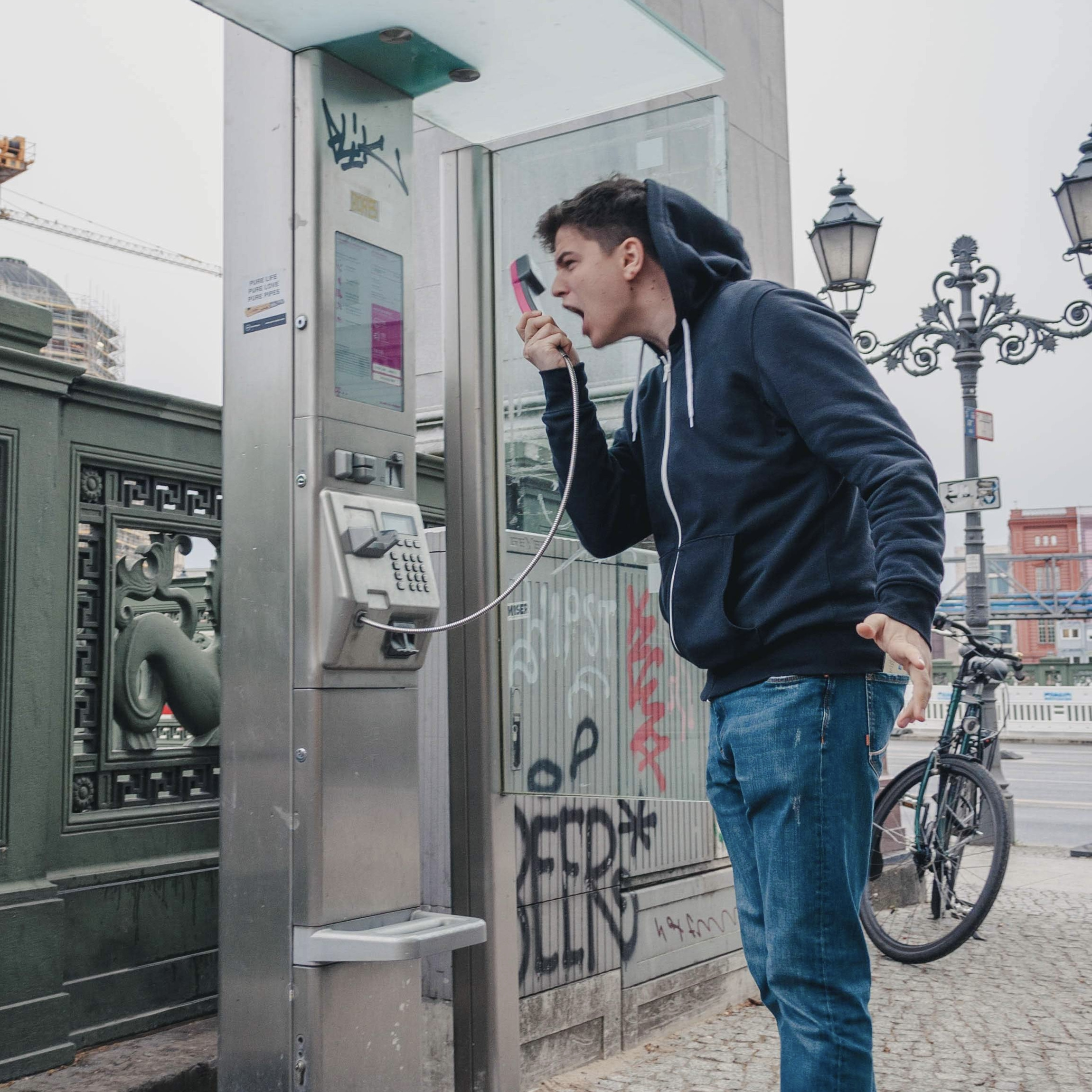 man yelling in a pay phone