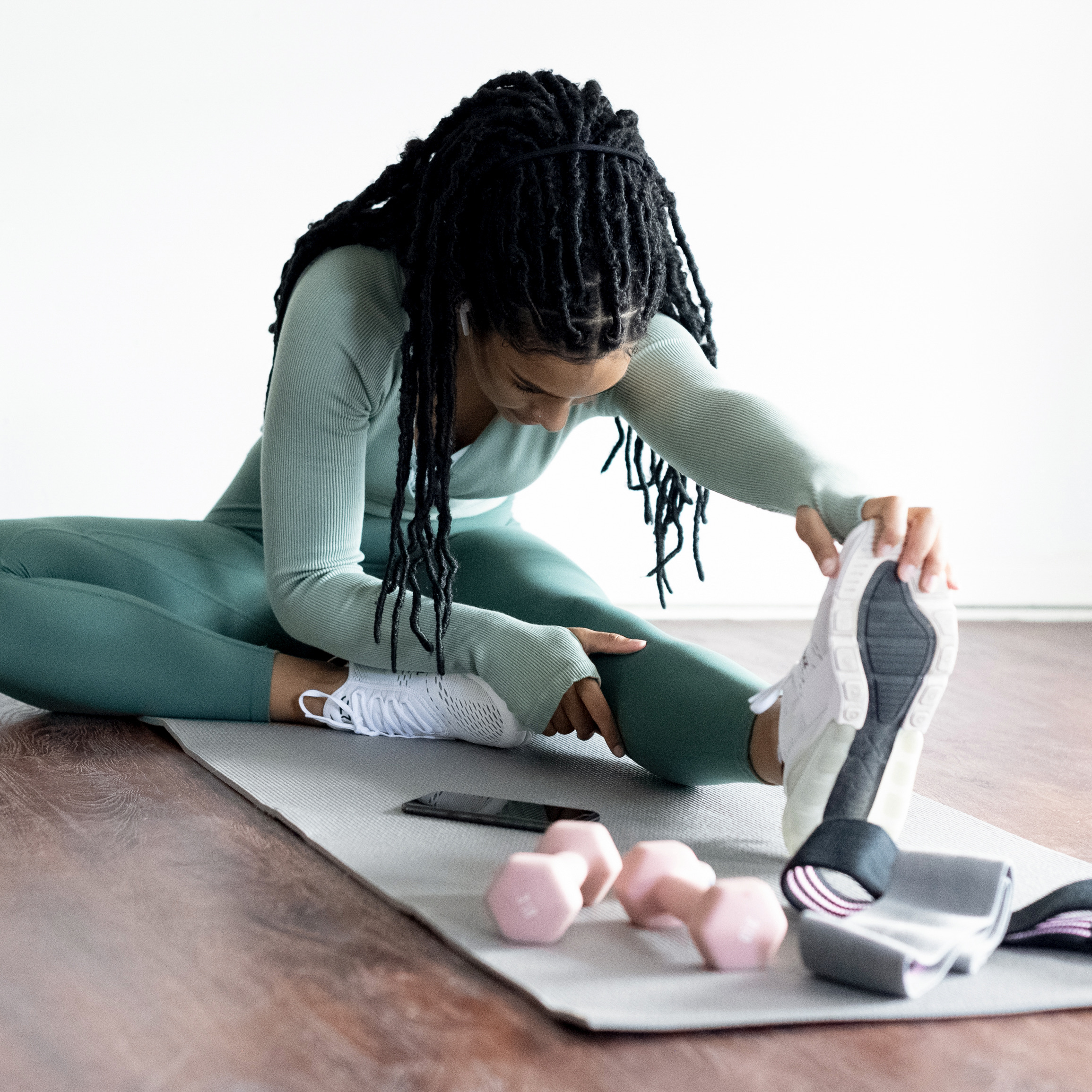 girl sitting on exercise mat with pink weights and stretching | 15 healthy daily habits \ Positively Jane
