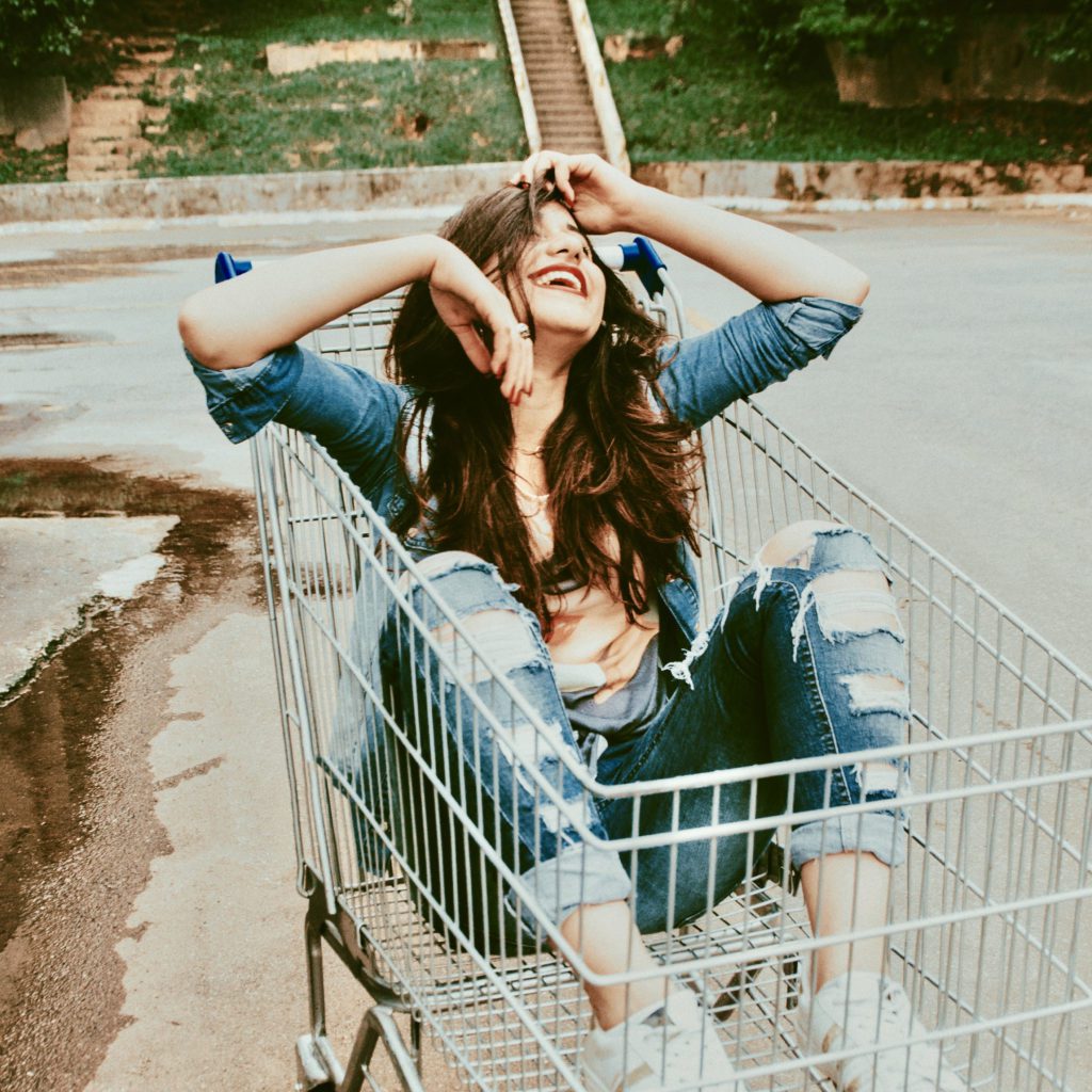 Girl sitting in a shopping cart laughing | where do emotions come from | Positively Jane