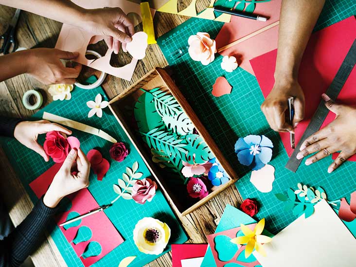 many hands reaching for some type of paper craft | can crafting improve your mood | Positively Jane  