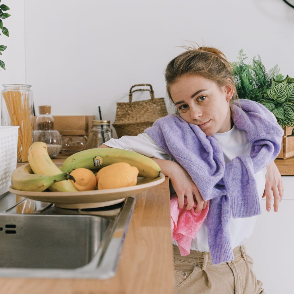 woman leaning against kitchen counter with veggies on a tray. she is looking discouraged | eliminate the overwhelm | the 5 minute declutter | Positively Jane