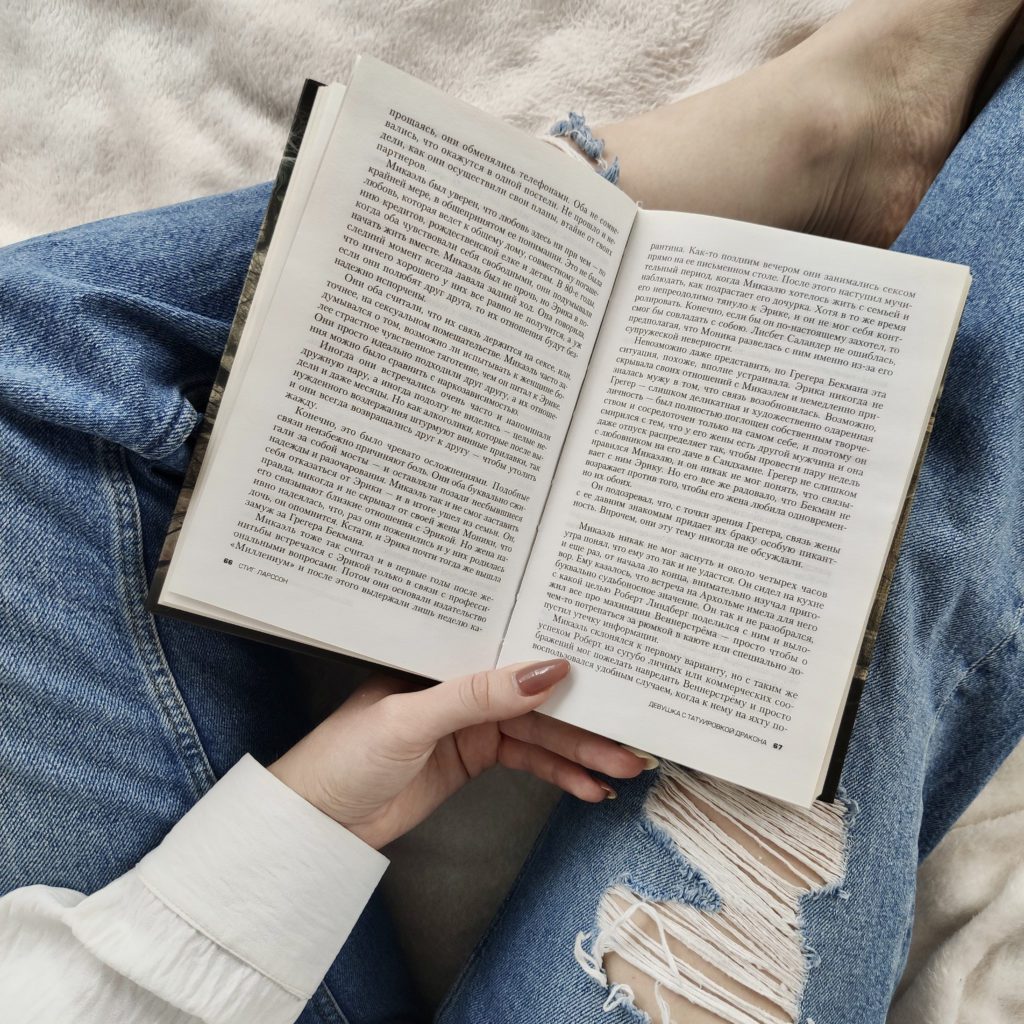 girl reading a book. You see her book, hand and ripped jeans | healthy daily habits | Positively Jane  