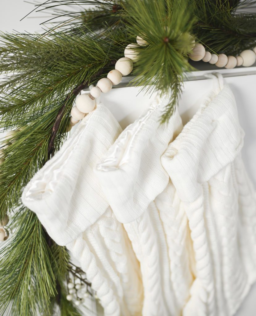 white stockings hanging from a white mantle with green garland | finding joy in the holidays | Positively Jane  