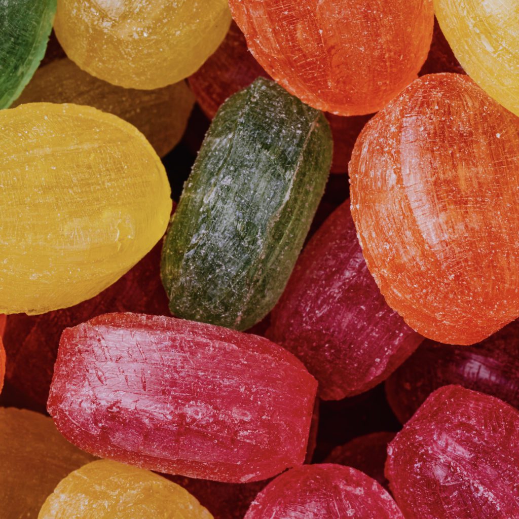 unwrapped and colorful hard candy in a pile | how to teach kids about money | Positively Jane