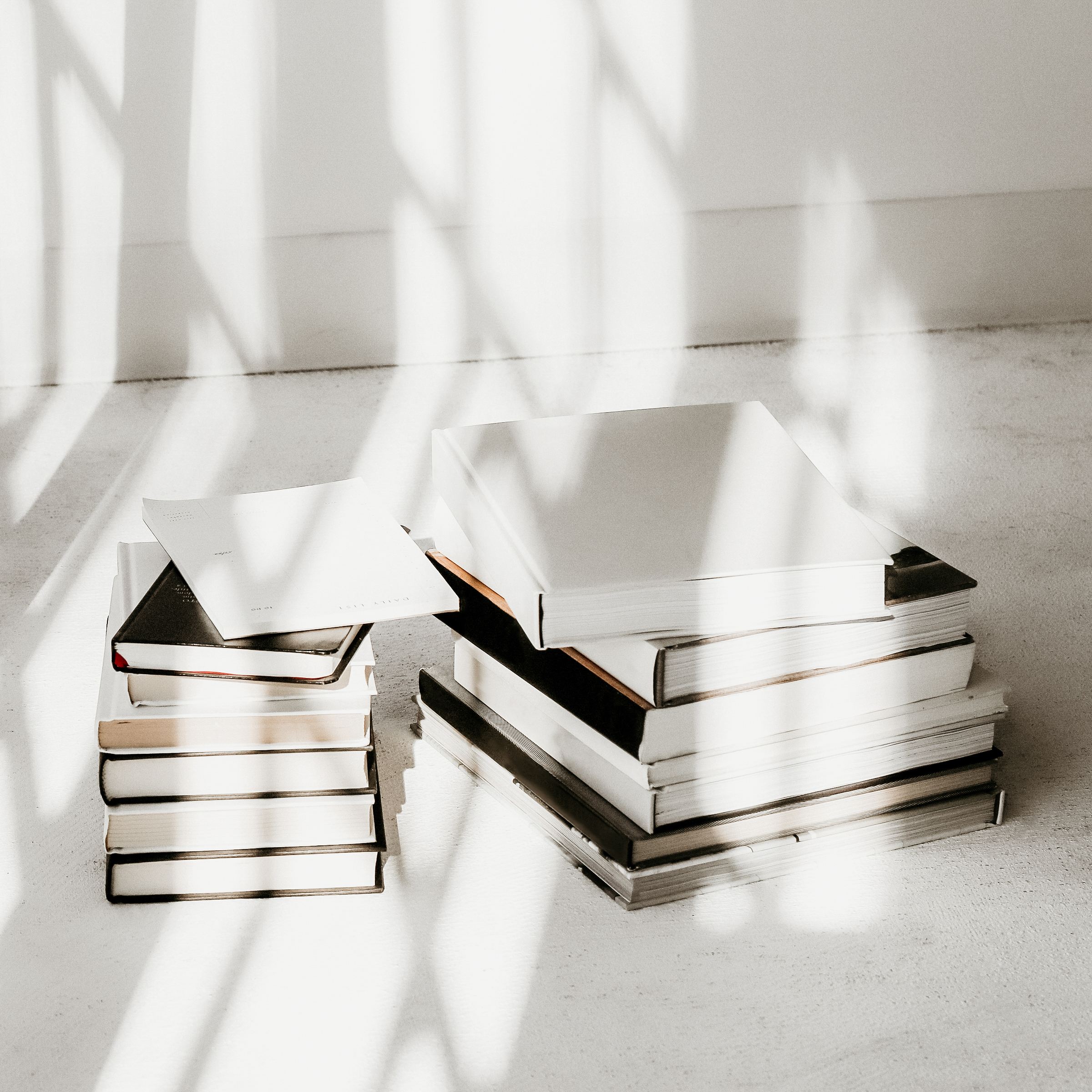 books piled up on a table. The background is white and the books are neutral in color | what I learned in 3 years as a blogger | positively Jane
